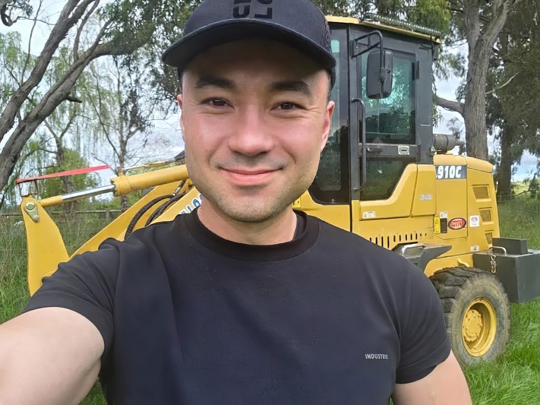 Smiling on the farm in front of a loader